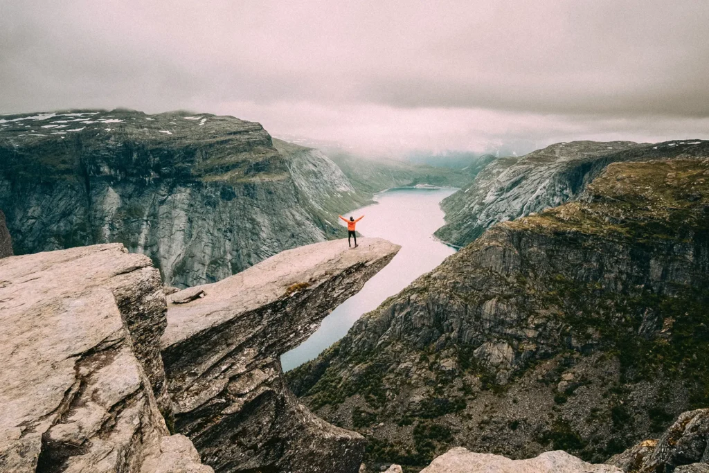 Vakkert landskap av Trolltunga i Vestland med en person står ytterst på steinformasjonen