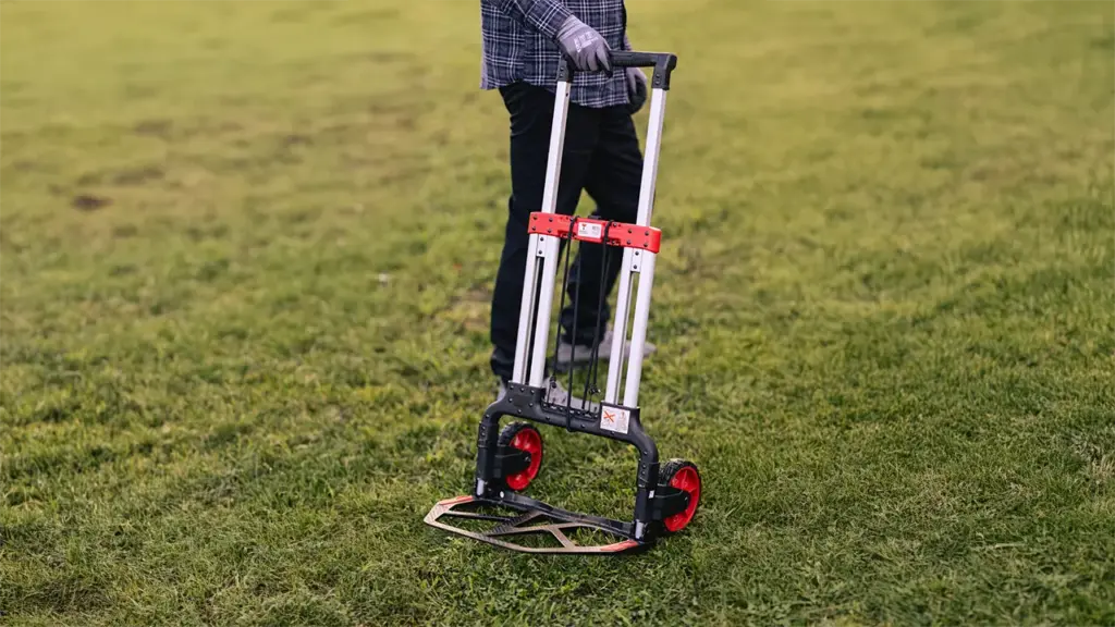 Sekketralle med tom lasterplate som holdes av en mann i ferd med å dytte den.